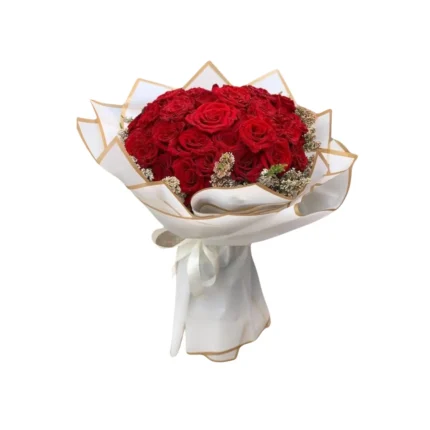 Bouquet de roses rouges Amour Royal, entouré de fleurs délicates et emballé dans un papier blanc élégant avec liseré doré.