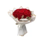 Bouquet de roses rouges Amour Royal, entouré de fleurs délicates et emballé dans un papier blanc élégant avec liseré doré.