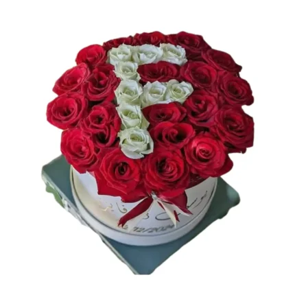 Arrangement floral en forme de lettre F avec roses rouges et blanches dans une boîte ronde – Fleuriste Marrakech